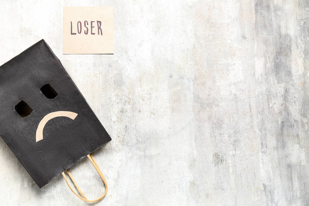 Paper bag with sad smile and word LOSER on grunge background - Photo, Image