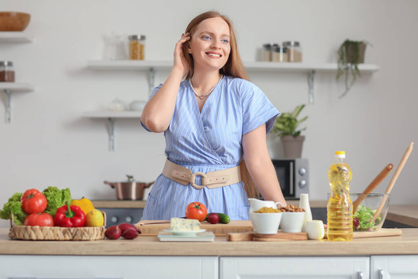 Jovem mulher fazendo salada de legumes na cozinha - Foto, Imagem
