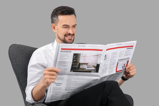 Hezký obchodník čtení novin v křesle na šedém pozadí - Fotografie, Obrázek