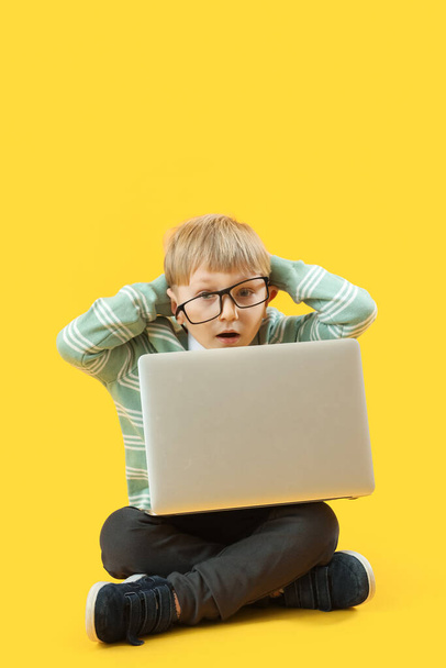 Empresário chocado com laptop sentado no fundo amarelo - Foto, Imagem