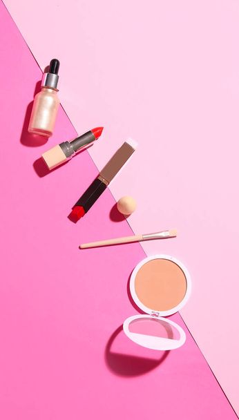 Lipsticks with powder, brush and sponge on pink background - Photo, Image