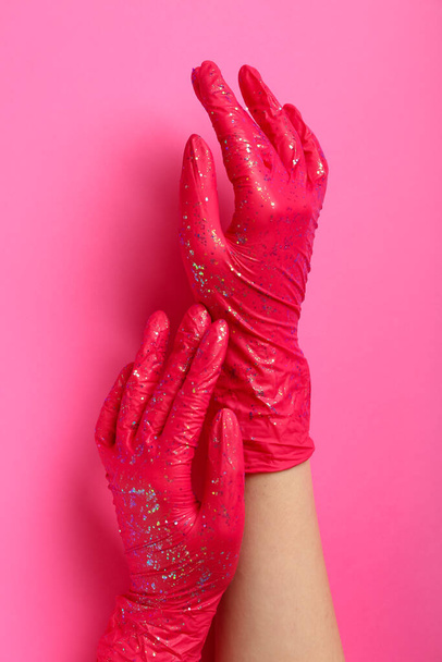 Woman in rubber gloves with glitter on pink background - Photo, image