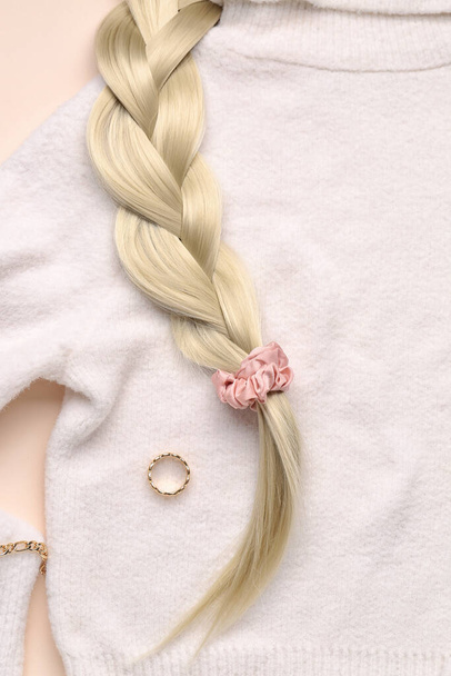 Плетені волосинки зі скребком, прикрасами та светром на бежевому фоні, крупним планом
 - Фото, зображення