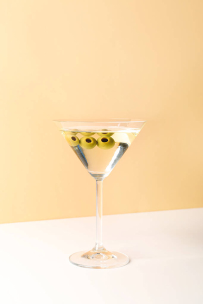 Glass of martini with olives on beige background - Photo, image