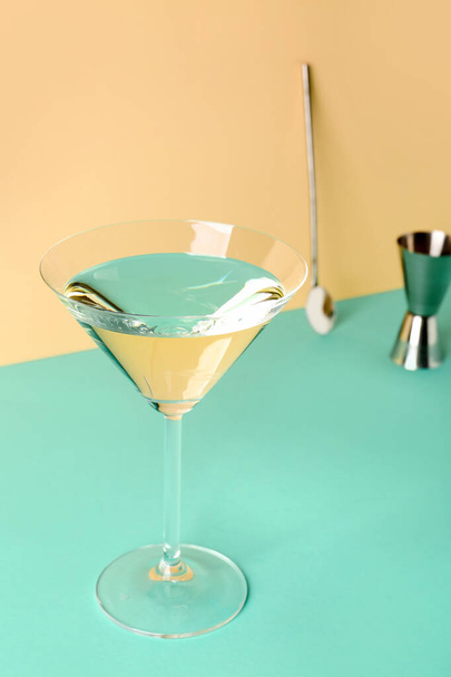Glass of martini, bar spoon and jigger on color background - Foto, imagen