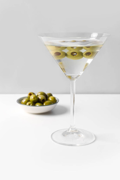 Glass of martini and olives on light background - Foto, Imagen