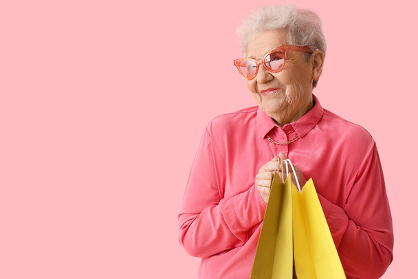Старша жінка з сумками на рожевому фоні
 - Фото, зображення