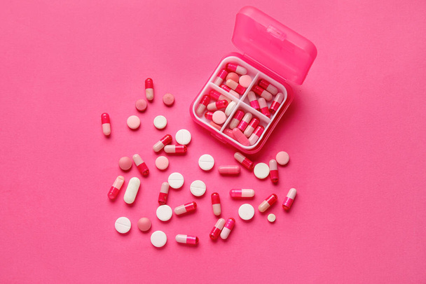 Conteneur avec pilules sur fond rose - Photo, image