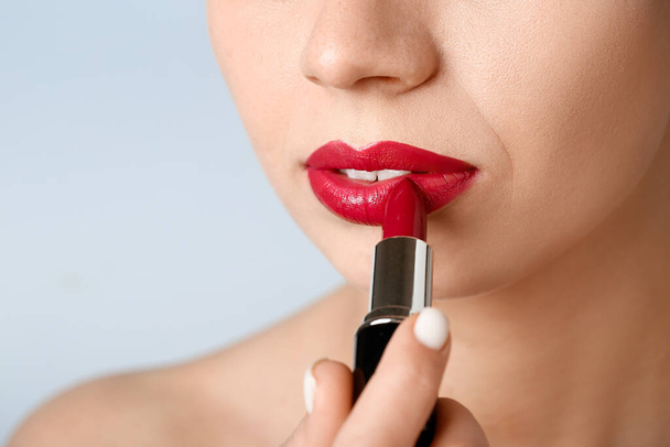 Woman applying red lipstick on grey background, closeup - Fotoğraf, Görsel