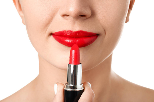 Nainen, joka käyttää punaista huulipunaa valkoisella taustalla, lähikuva - Valokuva, kuva