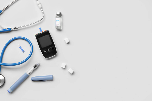 Glucometer with sugar, insulin and stethoscope on grey background. Diabetes concept - Photo, Image