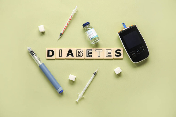 Word DIABETES with glucometer, insulin, lancet pen and sugar on green background. Diabetes concept - Fotó, kép