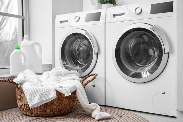 Kosár koszos ruhákkal mosógép közelében a mosókonyhában - Fotó, kép