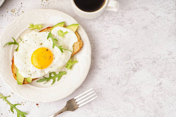 Hafif arka planda kızarmış yumurta, roka ve avokado ile nefis sandviç. - Fotoğraf, Görsel