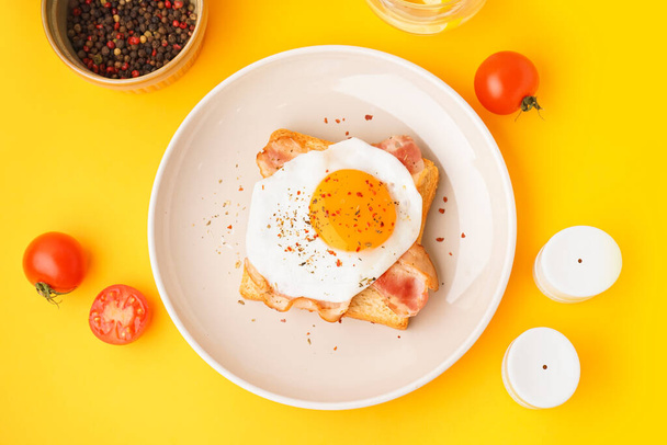 Delicious sandwich with fried egg and bacon on yellow background - Photo, Image