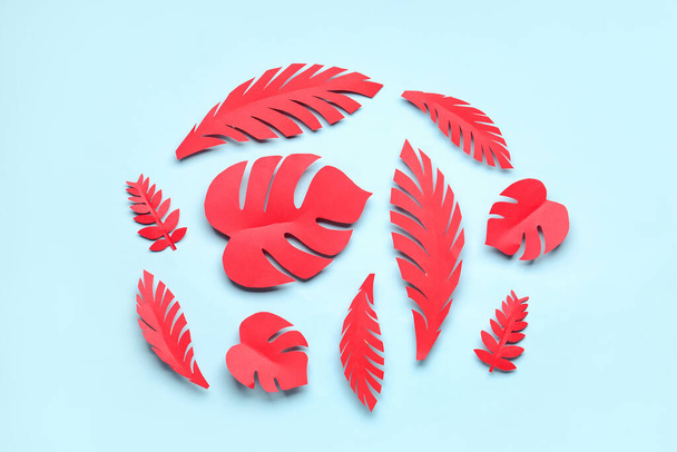 Red paper tropical leaves on blue background - Foto, imagen