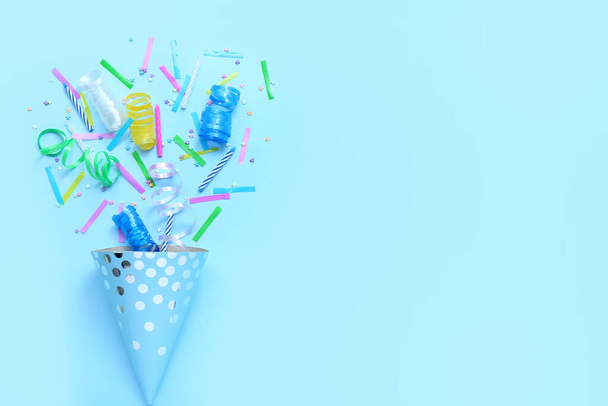 Cône de fête avec confettis et serpentine sur fond bleu. Célébration Journée des enfants - Photo, image