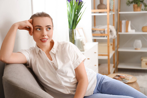 Huomaavainen nuori nainen istuu nojatuolissa kotona - Valokuva, kuva
