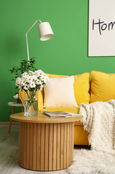 Интерьер гостиной с желтым диваном, лампой и журнальным столиком - Фото, изображение