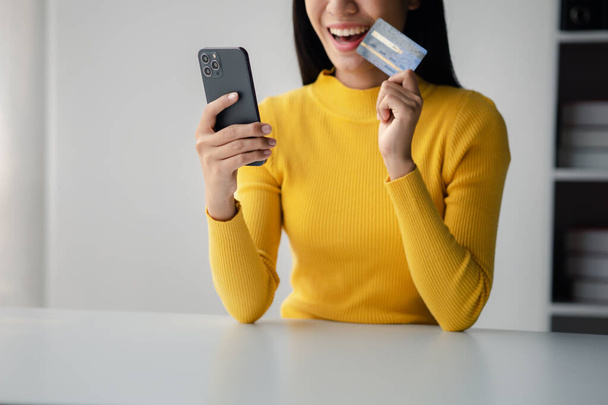Beautiful woman holding a credit card, she uses a credit card to pay for goods and services online, the concept of using a credit card for online shopping, ordering goods and services on the website. - Zdjęcie, obraz