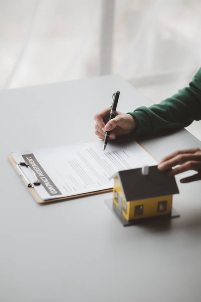 The salesperson of the housing estate in the project is preparing and verifying the contract of sale for the customer who will enter the contract. Concept of selling housing estates and real estate. - Фото, зображення