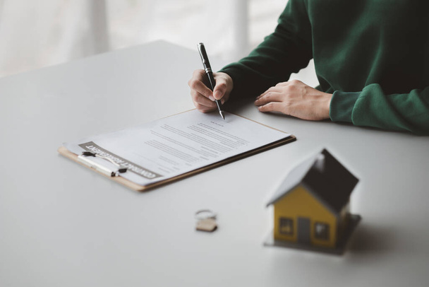 The salesperson of the housing estate in the project is preparing and verifying the contract of sale for the customer who will enter the contract. Concept of selling housing estates and real estate. - Фото, зображення