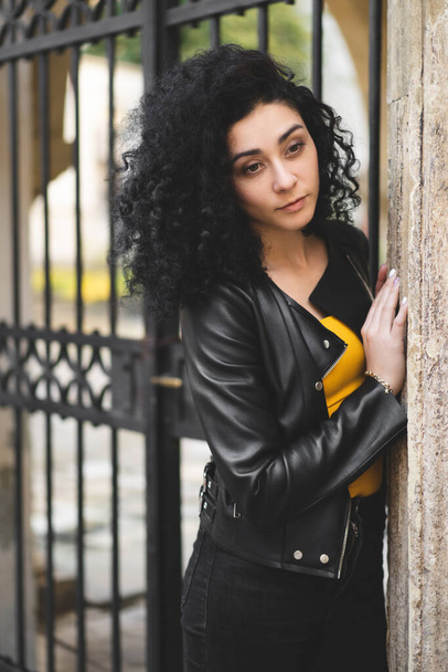 a beautiful girl in a leather jacket poses against the background of the city - Foto, afbeelding