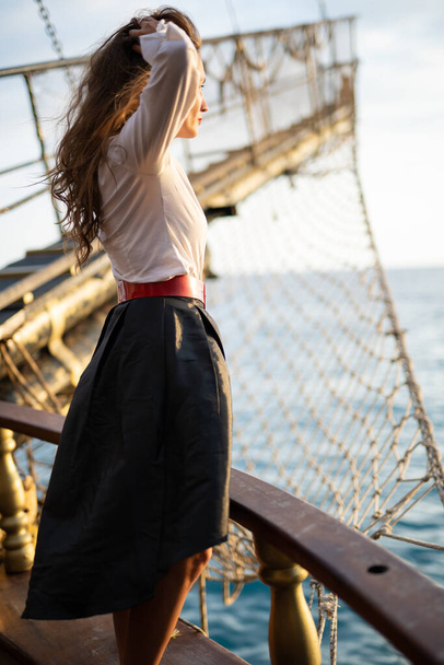 Egy gyönyörű lány kalóz jelmezben egy hajó fedélzetén. - Fotó, kép