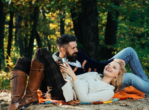 Autumn couple in love hug. Young lovers enjoying each other at a picnic. Woman lying down on the mans leg and having a romantic moment together. Beautiful autumn outside. Couple in loving - Фото, зображення