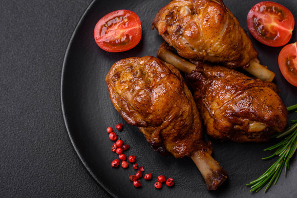 Delicious grilled chicken legs with spices and herbs in teriyaki sauce on a dark concrete background - 写真・画像