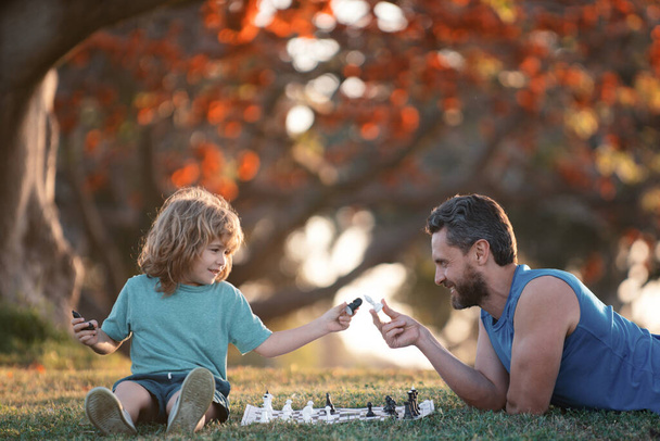 Father and son child playing chess spending time together in park - Foto, afbeelding