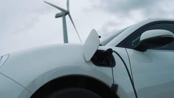 Progressieve toekomstige energie-infrastructuur concept van elektrisch voertuig wordt opgeladen op laadstation aangedreven door groene en hernieuwbare energie van een windturbine met het oog op het behoud van het milieu. - Video