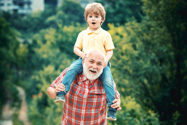 Grandfather and grandson enjoying outdoor. Daddy and boy smiling and hugging. Grandfather and grandson in the park. Concept of friendly family - Φωτογραφία, εικόνα