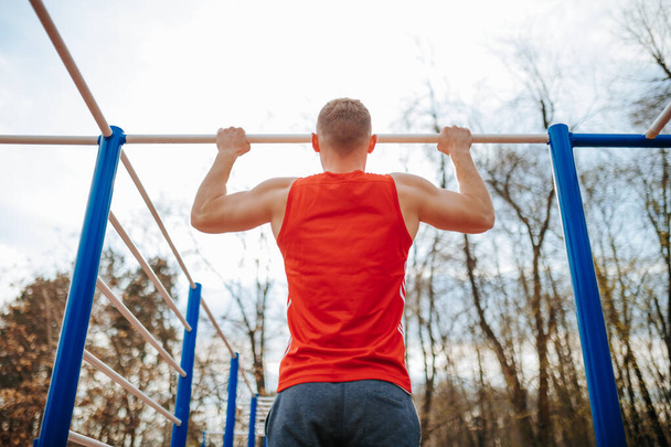 Improving Performance Male Athlete Using Pull-Up Bar for Training. A male athlete is using the pull-up bar for an intense training session, working on his form and technique to improve - 写真・画像