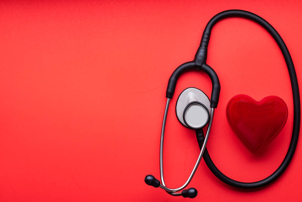 stethoscope and red heart on a red background. View from above. Space for text. - Fotó, kép