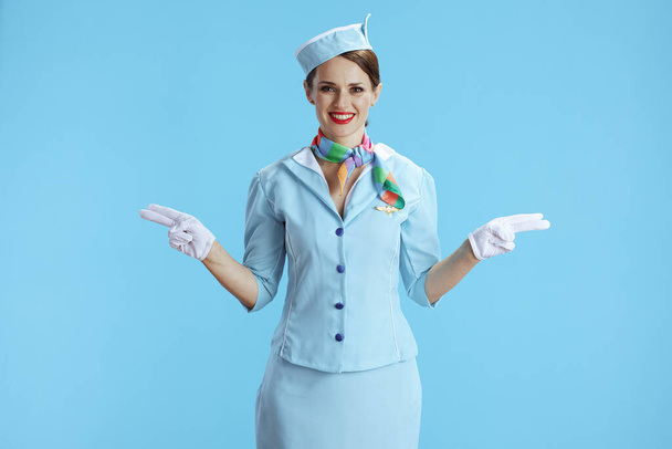 happy elegant air hostess woman isolated on blue background in blue uniform gesturing. - Фото, зображення
