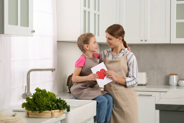 Little daughter congratulating mom with greeting card in kitchen. Happy Mother's Day - Fotoğraf, Görsel