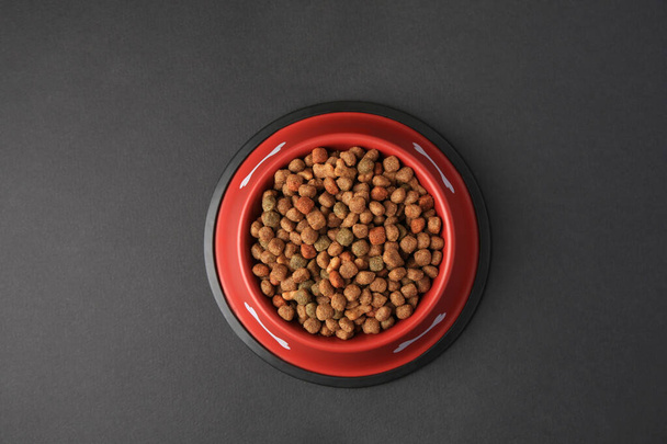Dry dog food in feeding bowl on black background, top view - Foto, Bild