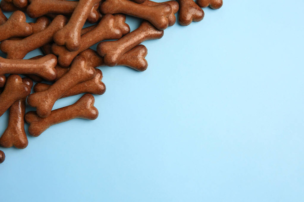 Bone shaped dog cookies on light blue background, flat lay. Space for text - Foto, Imagem