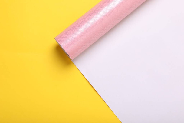 Roll of pink wrapping paper on yellow background, top view. Space for text - Fotografie, Obrázek