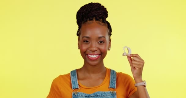 Porträt, Hörgerät und Daumen hoch mit einer schwarzen Frau auf gelbem Hintergrund, die Ja oder Danke sagt. Gehörlose, behinderte und ähnliche Geste mit einer glücklichen jungen Frau, die sich positiv oder fröhlich fühlt. - Filmmaterial, Video