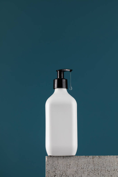 A white dispenser with a dripping drop of gel on a white shelf. The concept of routine body and hair care. - Foto, Imagem