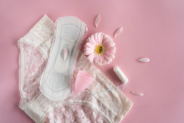 Menstruation period concept. Hygienic white female pad, Menstrual cup and tampon with pink flowers. Menstruation, protection. Womens health - Photo, Image
