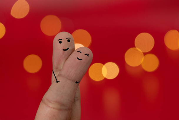 Los dedos felices y enamorados se unen con fondo rojo y efecto borroso, bokeh. Concepto de San Valentín. - Foto, imagen