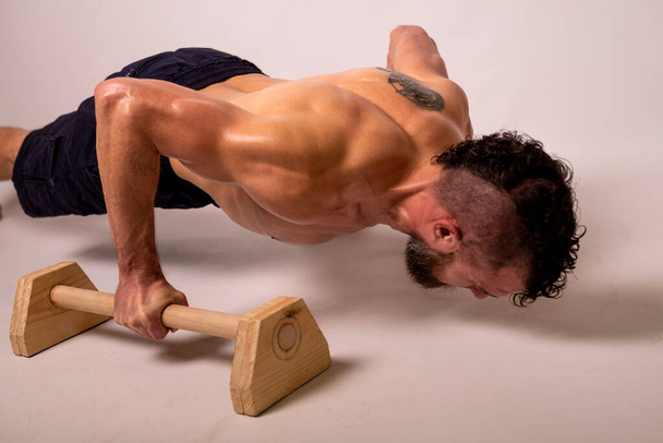 A young muscular man is doing push-ups on parapets. Sports lifestyle. - Photo, image