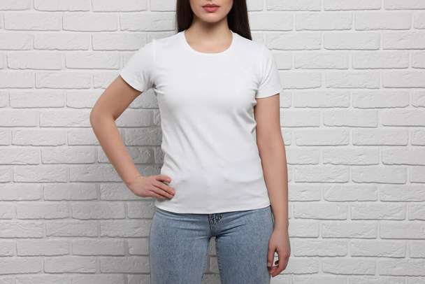 Woman wearing stylish T-shirt near white brick wall, closeup - Foto, imagen
