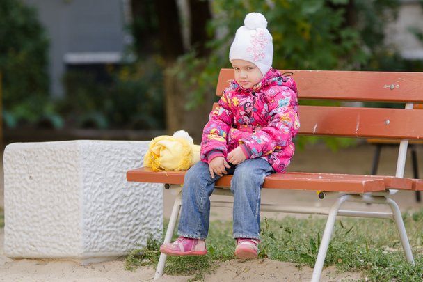 Fille sombre en vêtements d'automne assis sur un banc
 - Photo, image