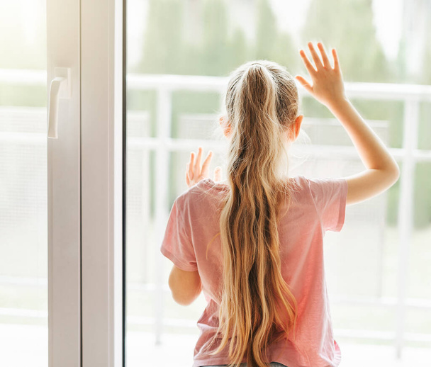 Самотня дівчинка з видом на вікно, стоячи вдома сама
.  - Фото, зображення