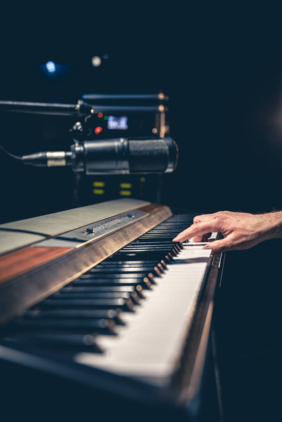 Karanlık müzik stüdyosunun içinde piyano tuşları çalan erkek el, stüdyo konseptini kaydediyor.. - Fotoğraf, Görsel