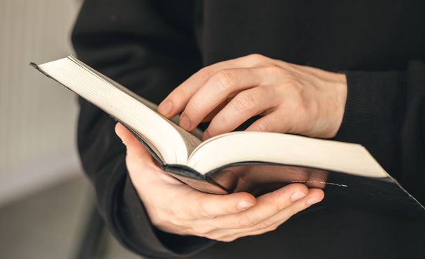 Open holy book Bible in male hands, close-up, the concept of Christianity, faith in God. - Foto, imagen
